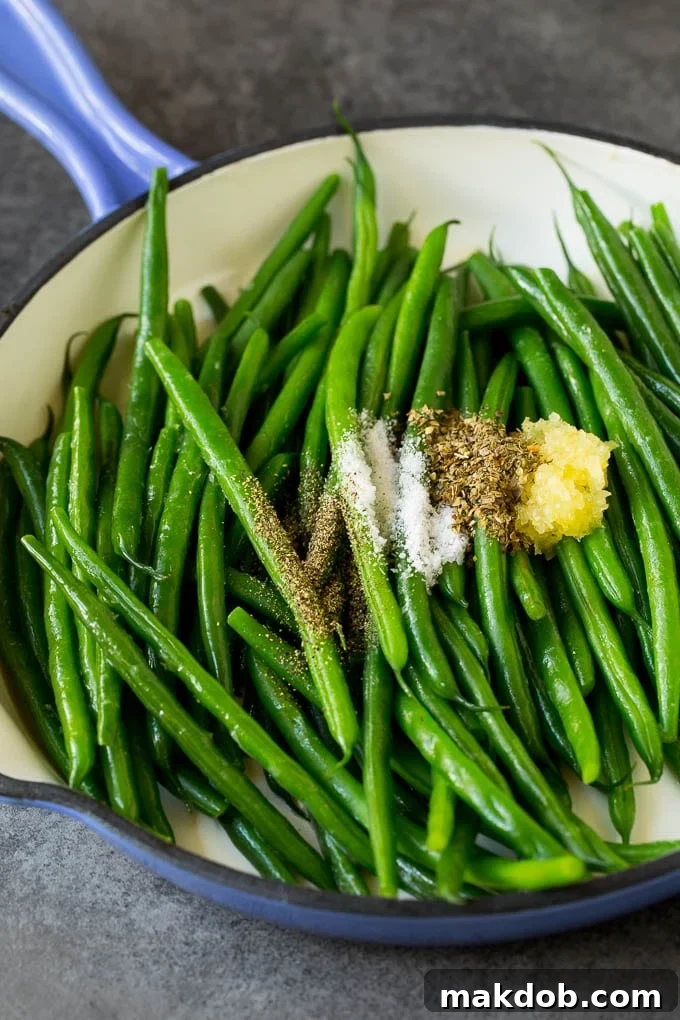 These sauteed green beans are cooked in butter, garlic and an assortment of fresh and dried herbs. Beans with garlic and seasonings in a pan.