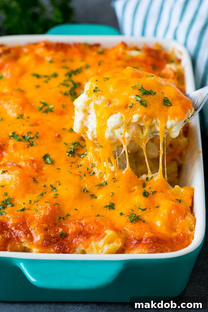 A spoon serving up a generous portion of golden-brown cheesy potatoes, garnished with fresh chopped parsley.