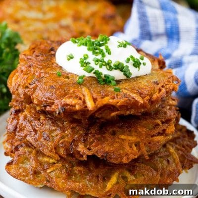 A stack of potato pancakes topped with sour cream and chives.