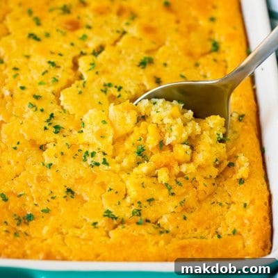 A dish of corn souffle with a serving spoon in it.