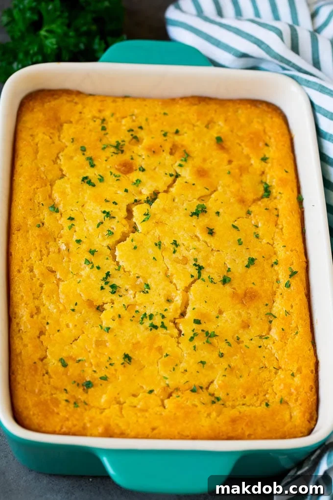 This corn souffle recipe is a flavorful blend of corn kernels, butter, eggs and creamed corn, all baked to light and fluffy perfection. Corn souffle in a baking dish, topped with vibrant parsley, ready to be served.