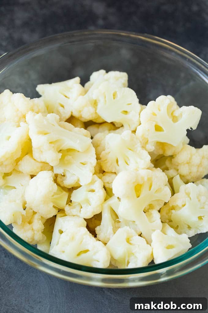 Freshly cooked cauliflower florets in a bowl, prepared for casserole assembly. A bowl filled with tender, cooked cauliflower florets, ready for the cheese sauce.