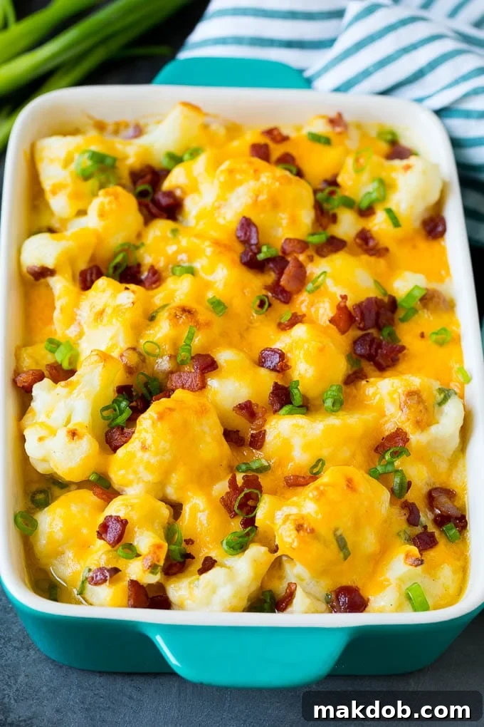 Irresistible baked cauliflower casserole with a golden, bubbly cheese topping. A baked cauliflower casserole, glistening with melted cheese, topped with crispy bacon and fresh green onions.