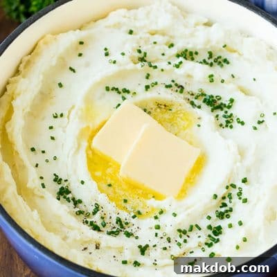 Velvety Cream Cheese Mash 2 A pot of cream cheese mashed potatoes topped with butter and chives, ready to be served.