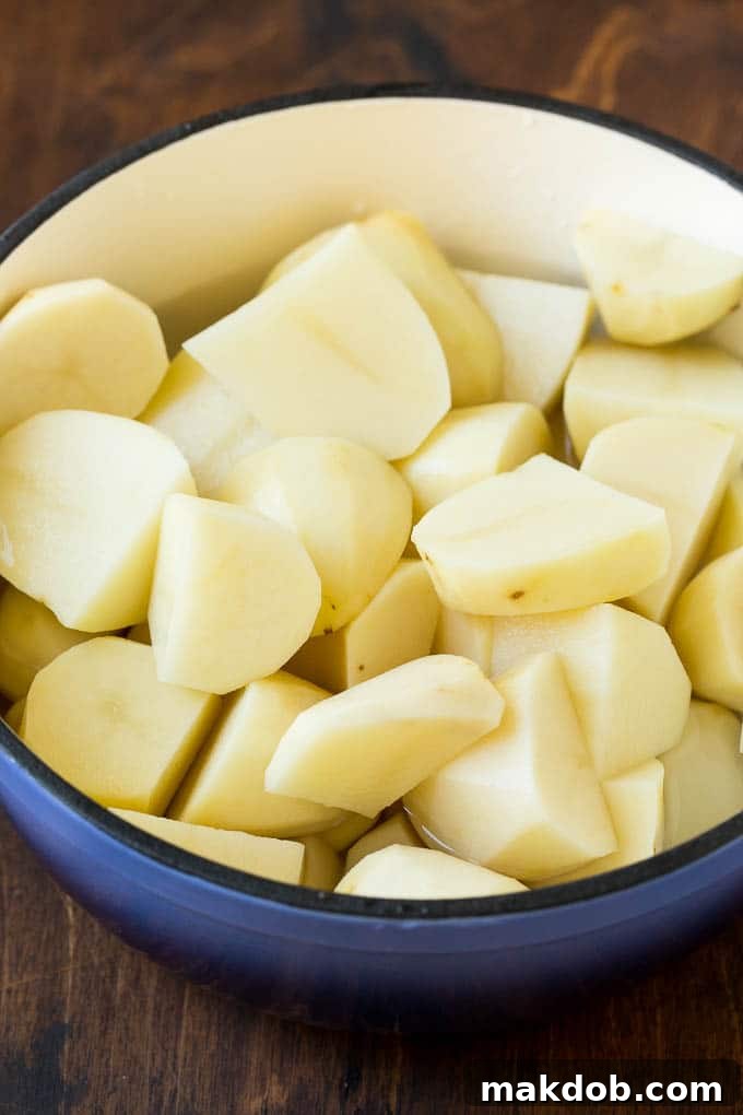 Peeled Potato Quarters in a Pot Peeled Russet potato quarters soaking in a pot of cold salted water, ready for boiling.