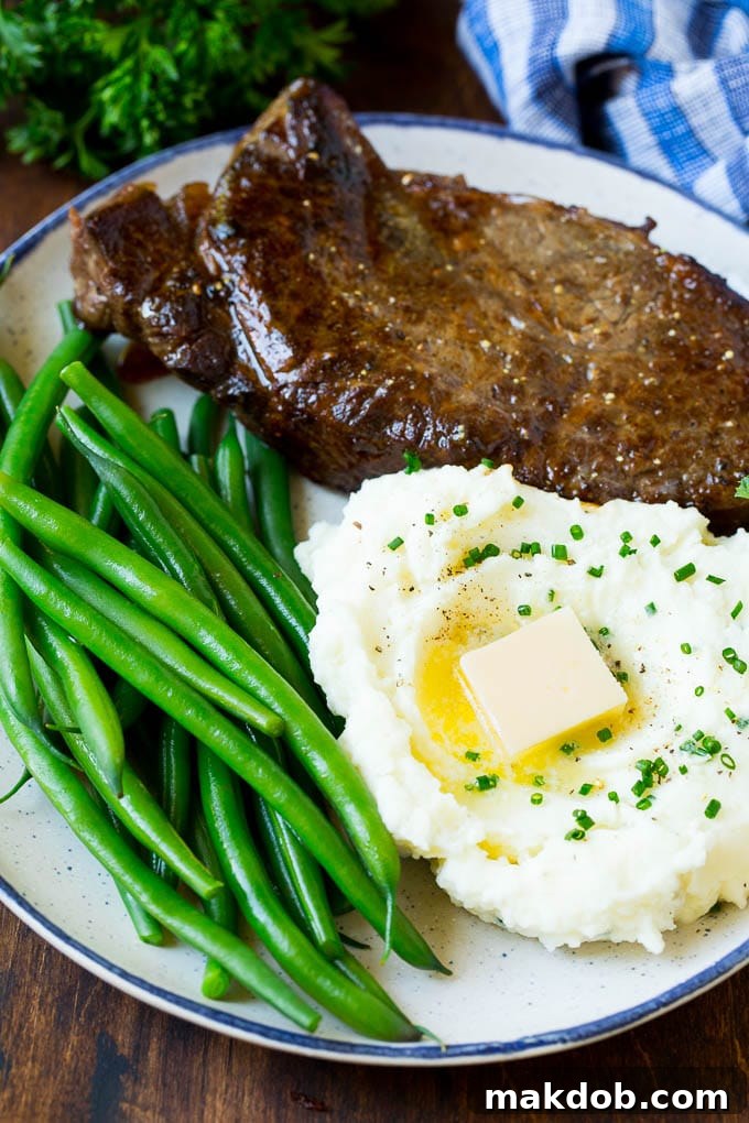 Cream Cheese Mashed Potatoes with Steak and Green Beans A hearty serving of cream cheese mashed potatoes, perfectly creamy, accompanied by a seared steak and fresh green beans, creating a complete and delicious meal.