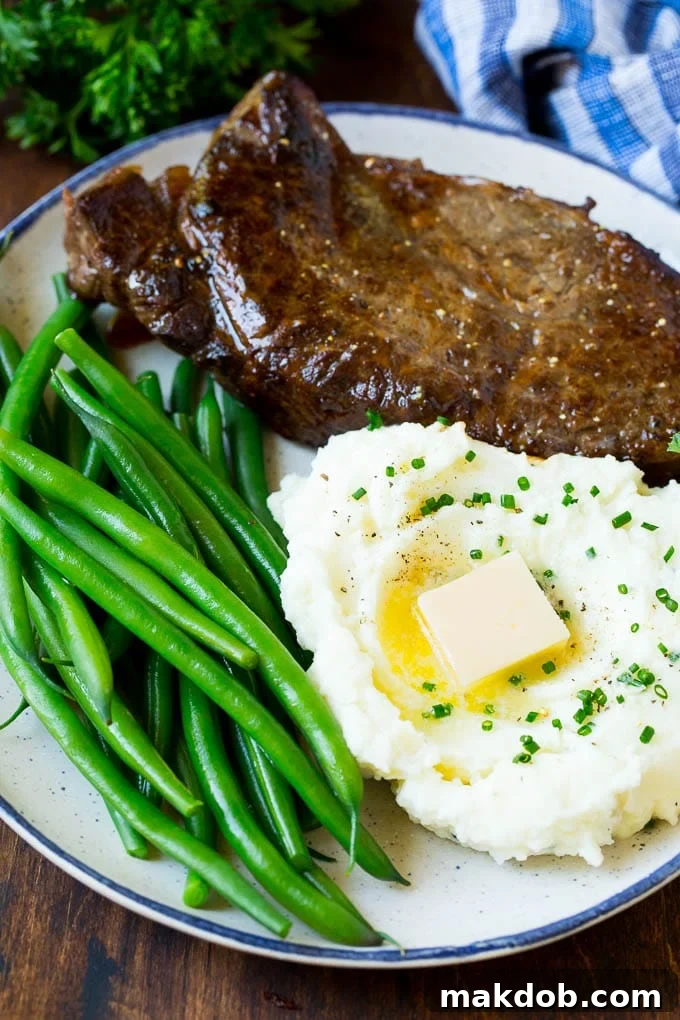 Cream cheese mashed potatoes served alongside a perfectly cooked steak and fresh green beans, creating a wholesome meal.