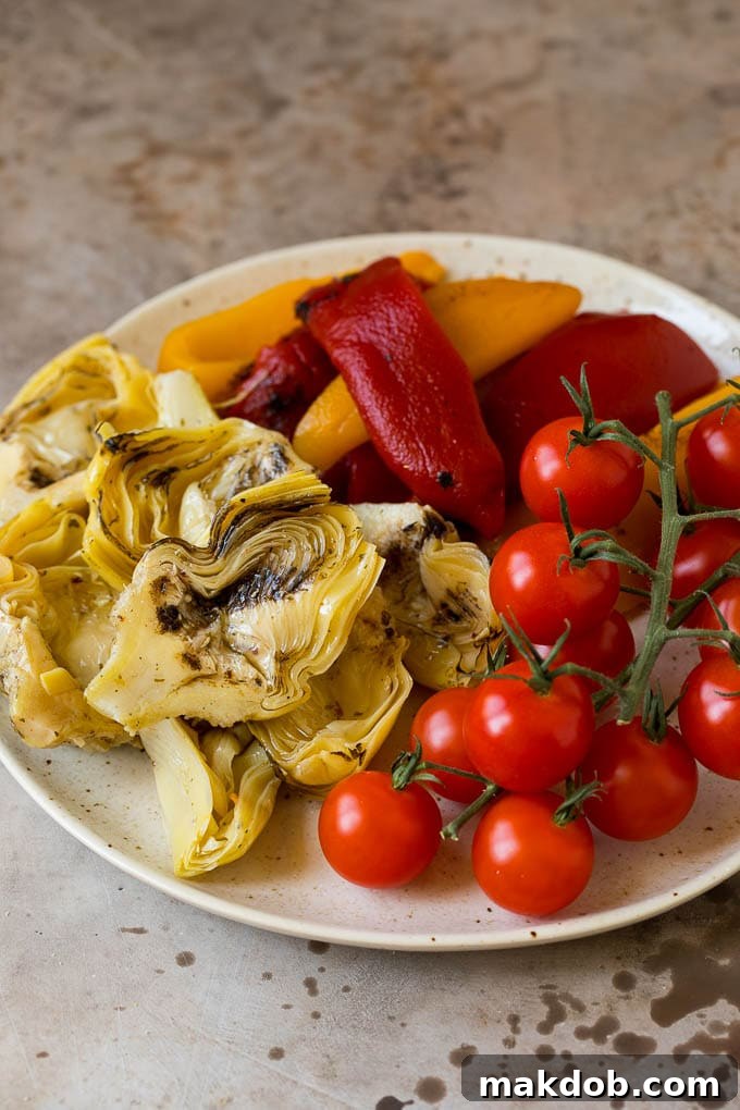 Roasted peppers, grilled artichokes and cherry tomatoes on a plate.