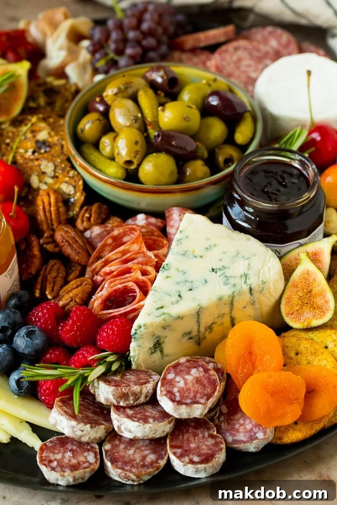 A charcuterie board close up with a wedge of cheese surrounded by salami, fruit and nuts.