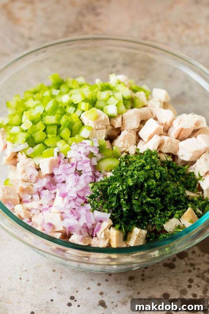 This turkey salad is a blend of diced turkey and colorful veggies, all tossed in a savory creamy dressing. Turkey, vegetables and parsley in a bowl.