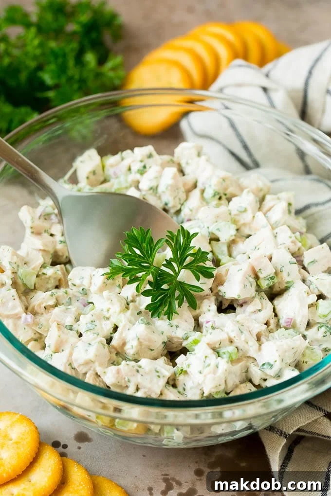 This turkey salad is a blend of diced turkey and colorful veggies, all tossed in a savory creamy dressing. A bowl of creamy turkey salad garnished with parsley and served with crackers.