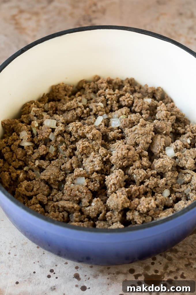This beef chili is a blend of meat, tomatoes, spices and beans, all simmered together to make a delicious and hearty meal. Cooked ground beef and onions in a pot.