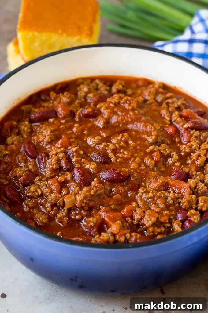 This beef chili is a blend of meat, tomatoes, spices and beans, all simmered together to make a delicious and hearty meal. A pot of beef chili with beans, served with cornbread.