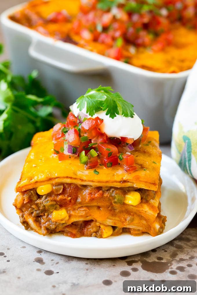 Ultimate Taco Lasagna 2 A vibrant slice of taco lasagna, garnished with fresh salsa, a dollop of sour cream, and a sprinkle of chopped cilantro, showcasing its delicious layers.