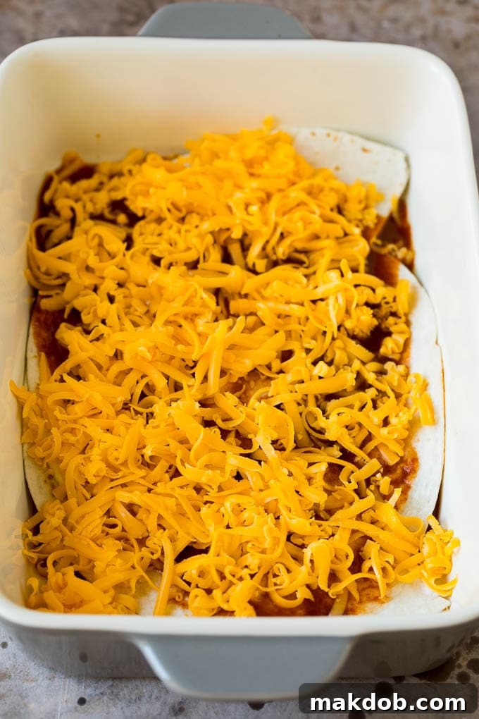 Ultimate Taco Lasagna 4 Layers of soft flour tortillas, rich enchilada sauce, and abundant cheese meticulously arranged in a baking dish, ready for the oven.