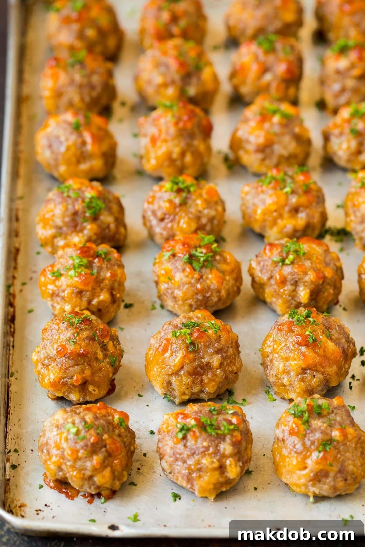 Easy Cheesy Sausage Balls 6 Cooked sausage balls on a pan, garnished with fresh parsley for a vibrant presentation.