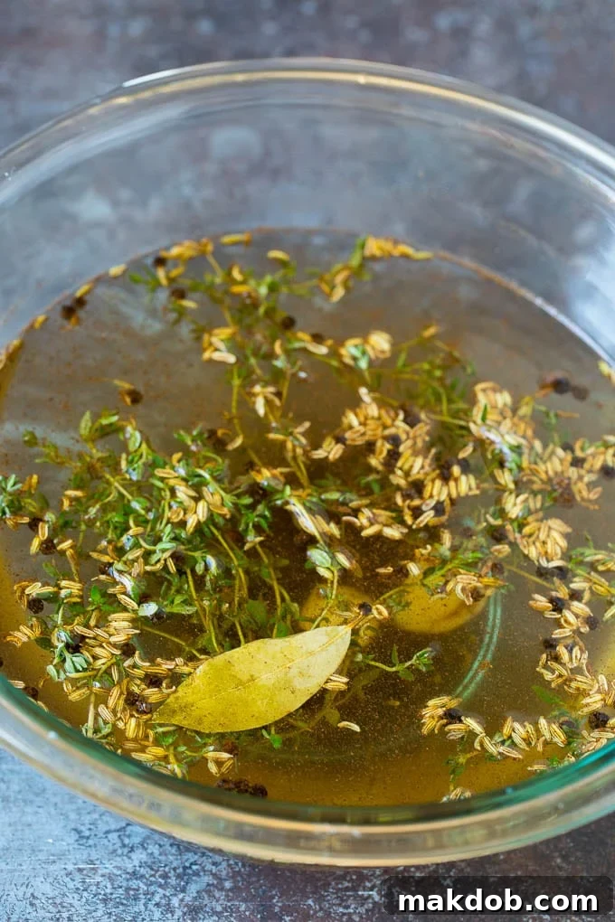 The aromatic brine mixture infusing pork chops with flavor. A close-up of a bowl filled with pork chop brine, highlighting the fennel seeds, thyme, pepper, and garlic infusing the liquid.