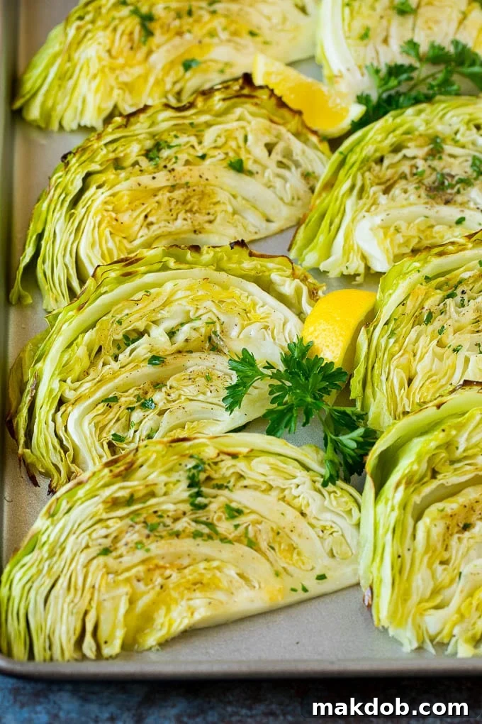This roasted cabbage recipe is wedges of cabbage seasoned with olive oil and spices, then oven baked until tender and browned. Golden brown roasted cabbage wedges on a baking pan, garnished with fresh parsley.