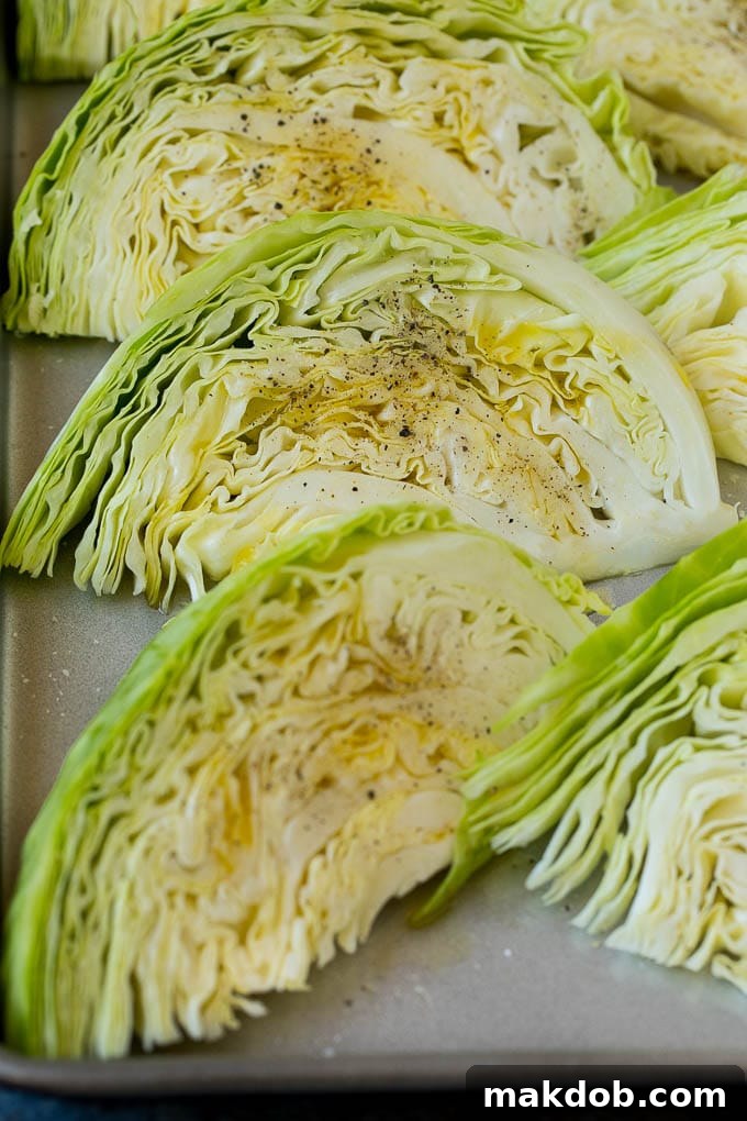This roasted cabbage recipe is wedges of cabbage seasoned with olive oil and spices, then oven baked until tender and browned. Raw cabbage wedges coated with olive oil and a blend of spices on a baking sheet.