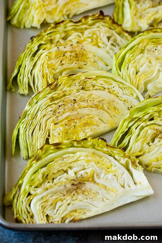 This roasted cabbage recipe is wedges of cabbage seasoned with olive oil and spices, then oven baked until tender and browned. Beautifully cooked cabbage wedges, tender and browned, resting on a sheet pan after roasting.