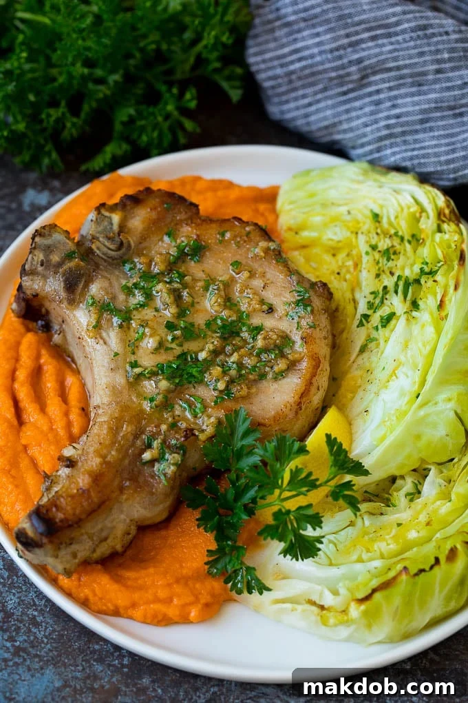 This roasted cabbage recipe is wedges of cabbage seasoned with olive oil and spices, then oven baked until tender and browned. A vibrant plate featuring roasted cabbage wedges, served alongside perfectly cooked pork chops and sweet potatoes.