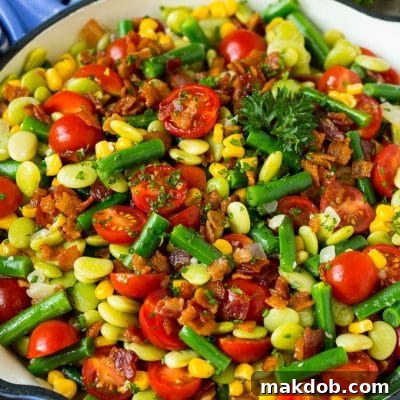 A skillet of succotash topped with bacon and herbs.