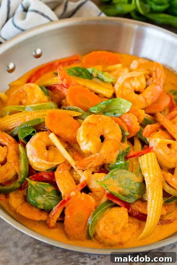 A pan of shrimp curry with assorted vegetables and fresh basil.