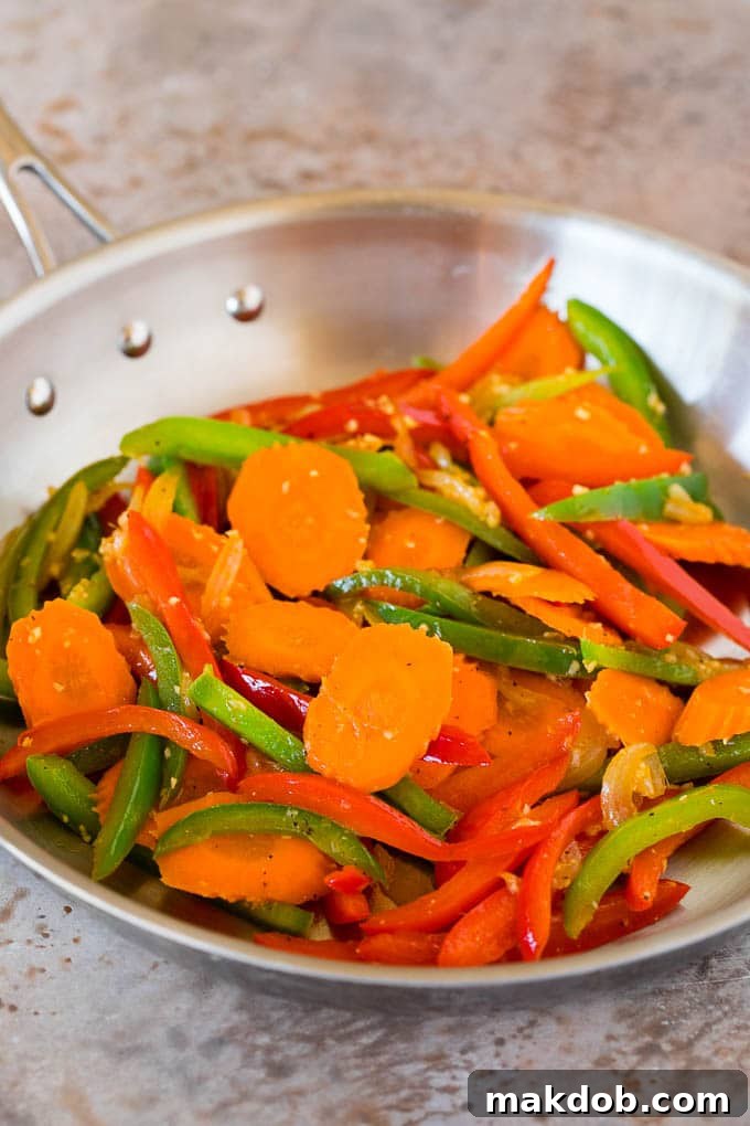 Sauteed carrots and peppers in a pan.