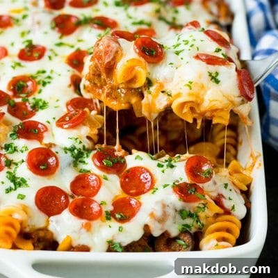 A spoon serving up a portion of pizza casserole, highlighting the melted cheese, tender pasta, and savory toppings.