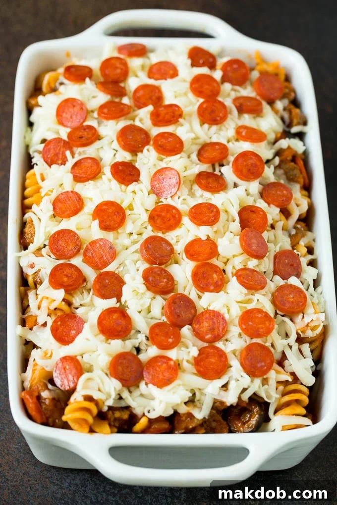 Pasta in a casserole dish topped with cheese and pepperoni, baked to golden-brown perfection. A freshly baked pizza casserole in a glass baking dish, beautifully topped with melted, golden-brown mozzarella cheese and scattered mini pepperoni, bubbling hot and fresh from the oven, ready to be served.