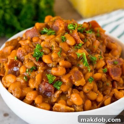 Chuckwagon Chili Beans 2 A bowl of cowboy beans topped with parsley and served with cornbread.