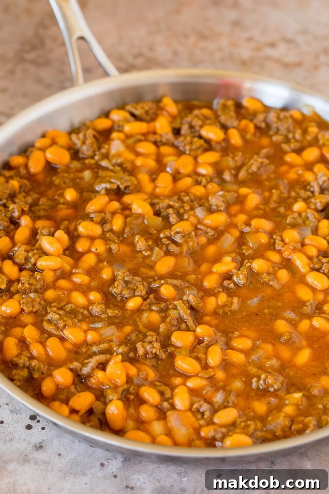 Beans and Beef Mixture in a Pan A large skillet containing beans, browned ground beef, and a savory sauce mixture, ready for the oven.