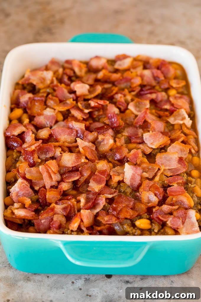 Baking Dish Ready for the Oven A ceramic baking dish filled with the cowboy bean mixture, topped with diced bacon, ready to be placed into the oven.