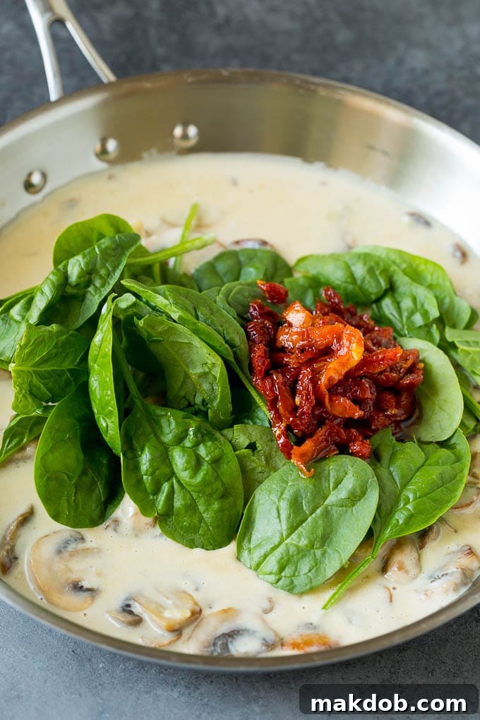 A pan filled with creamy mushroom sauce, vibrant spinach, and tangy sun-dried tomatoes.