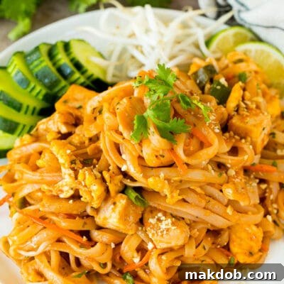 A plate of chicken pad thai served with bean sprouts and cucumber.