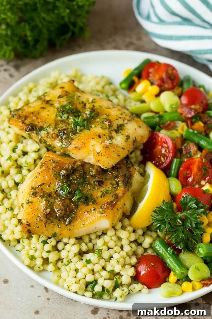 This baked cod is marinated with olive oil, garlic and fresh herbs, then roasted to tender and flaky perfection. Baked cod served with couscous and mixed vegetables.
