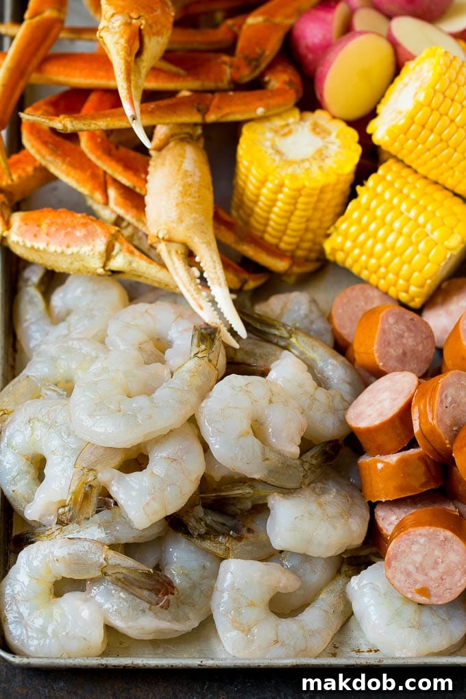 This Low Country Boil is a blend of shrimp, crab, sausage, corn and potatoes, all cooked together to create a hearty dinner. Shrimp, sliced sausage, crab legs and corn cobs on a sheet pan.