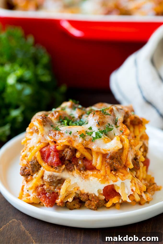 Million Dollar Spaghetti Casserole with melted cheese A perfectly golden-brown slice of Million Dollar Spaghetti Casserole topped with melted, bubbly cheese and fresh parsley, ready to be served.