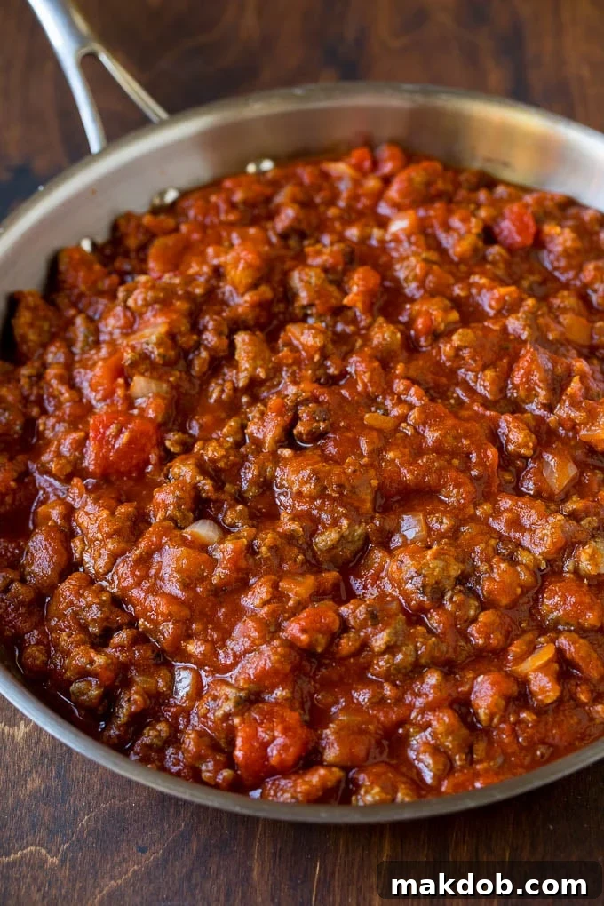 Homemade meat sauce simmering Rich, homemade meat sauce simmering in a large pan with onions and garlic, ready to be combined with pasta.
