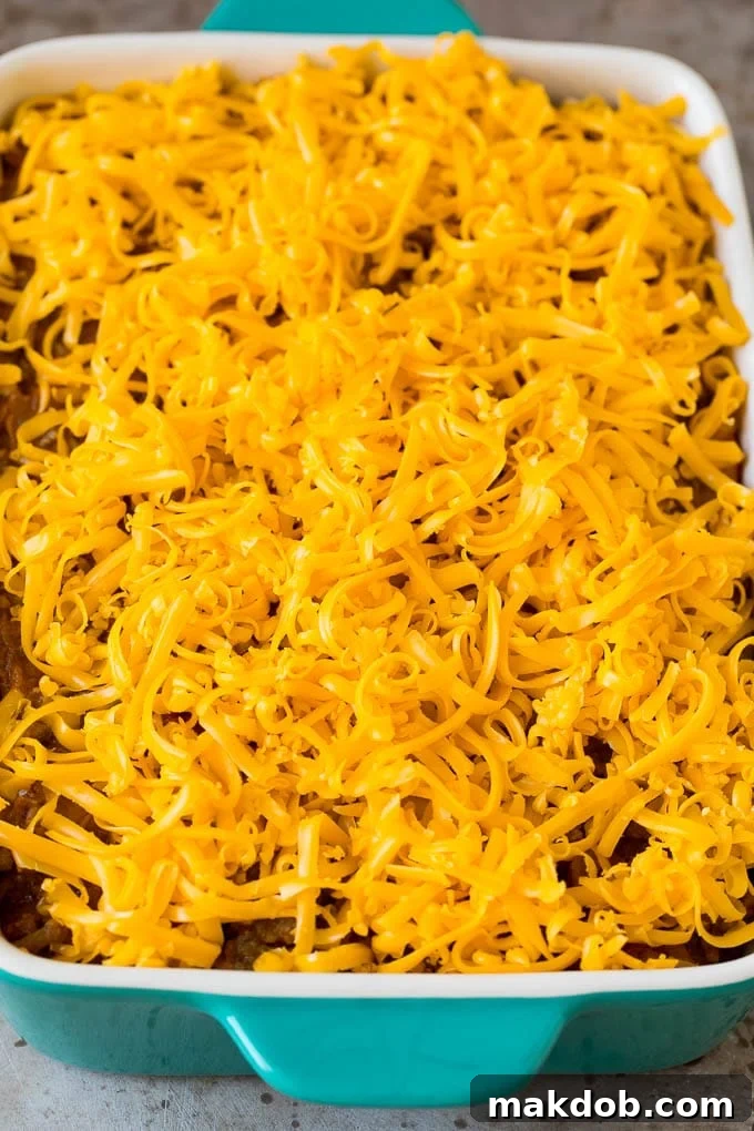 Layers of chips, meat and shredded cheese in a dish.