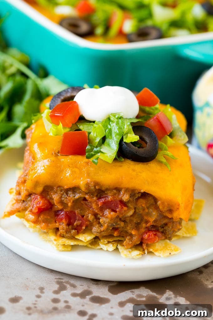 A slice of taco bake with a crust of tortilla chips and a filling of beef and beans.