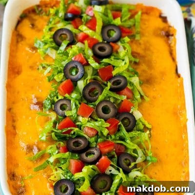 Taco bake topped with melted cheese, lettuce, tomatoes and olives.