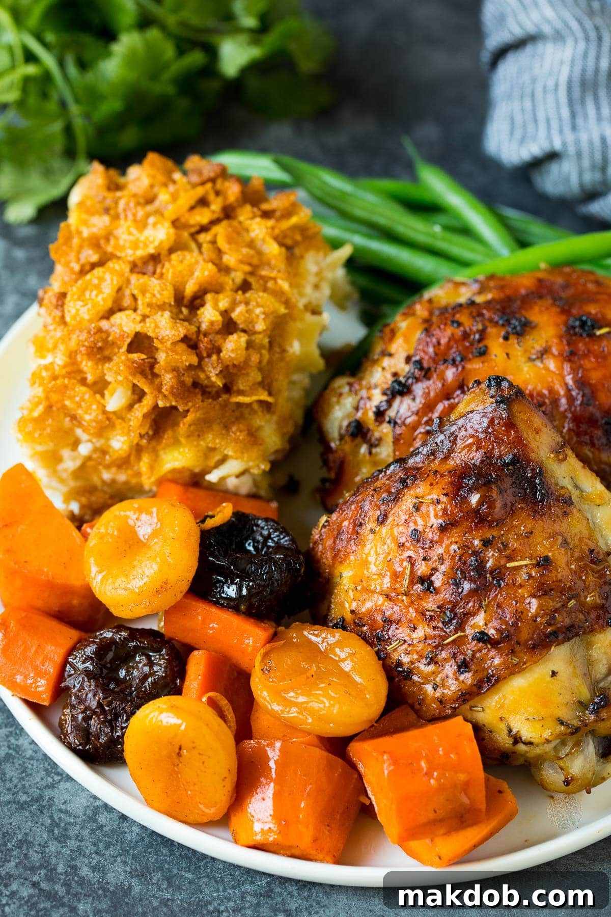 Sweet and Savory Holiday Tzimmes 6 A festive plate showcasing a generous serving of Tzimmes, beautifully paired with succulent roasted chicken and a golden portion of noodle kugel, creating a complete and inviting meal.