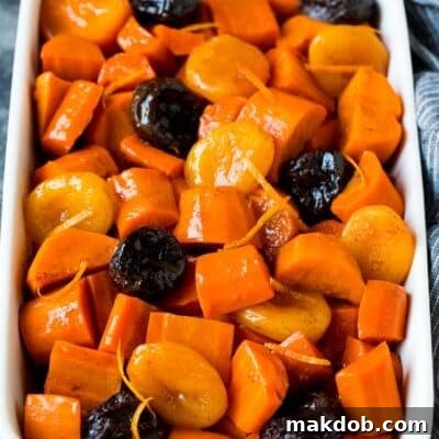 Sweet and Savory Holiday Tzimmes 7 A close-up shot of a rustic casserole dish brimming with perfectly cooked Tzimmes, showing its glossy sauce and tender pieces of sweet potato and dried fruit.