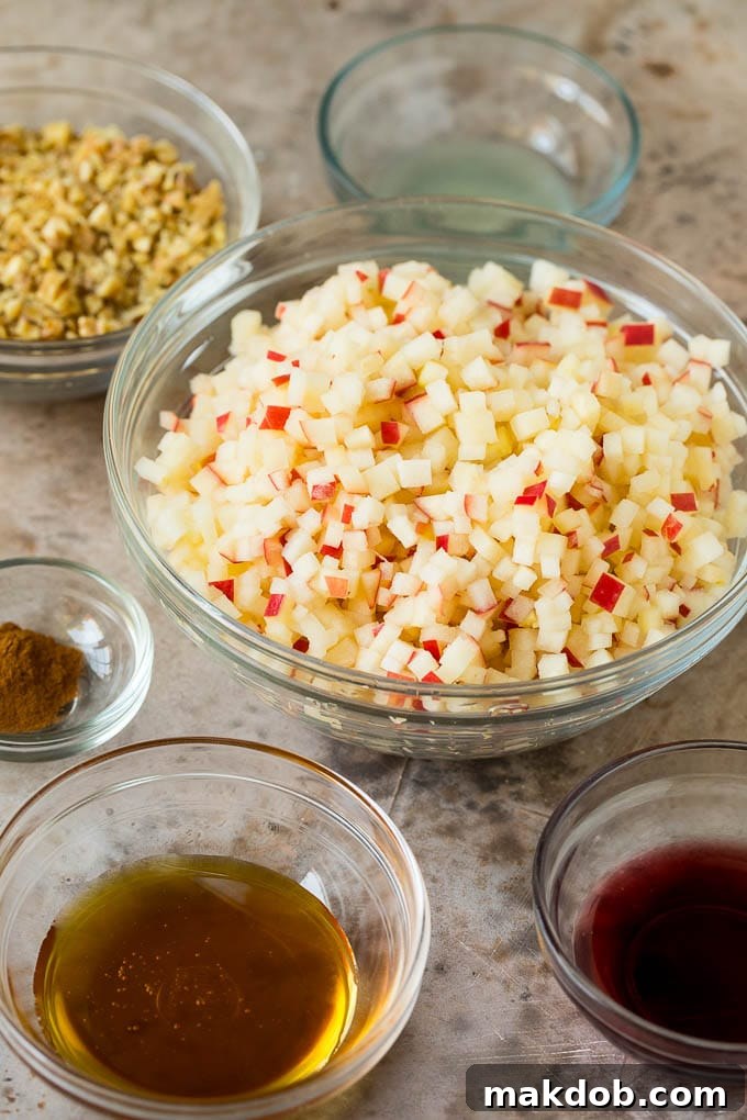 This charoset recipe is a blend of apples, walnuts and honey, all mixed together to make a sweet spread that's an essential part of any Passover meal. Bowls filled with the individual components of charoset: chopped apples, a jar of honey, a bottle of wine, and a bowl of cinnamon.
