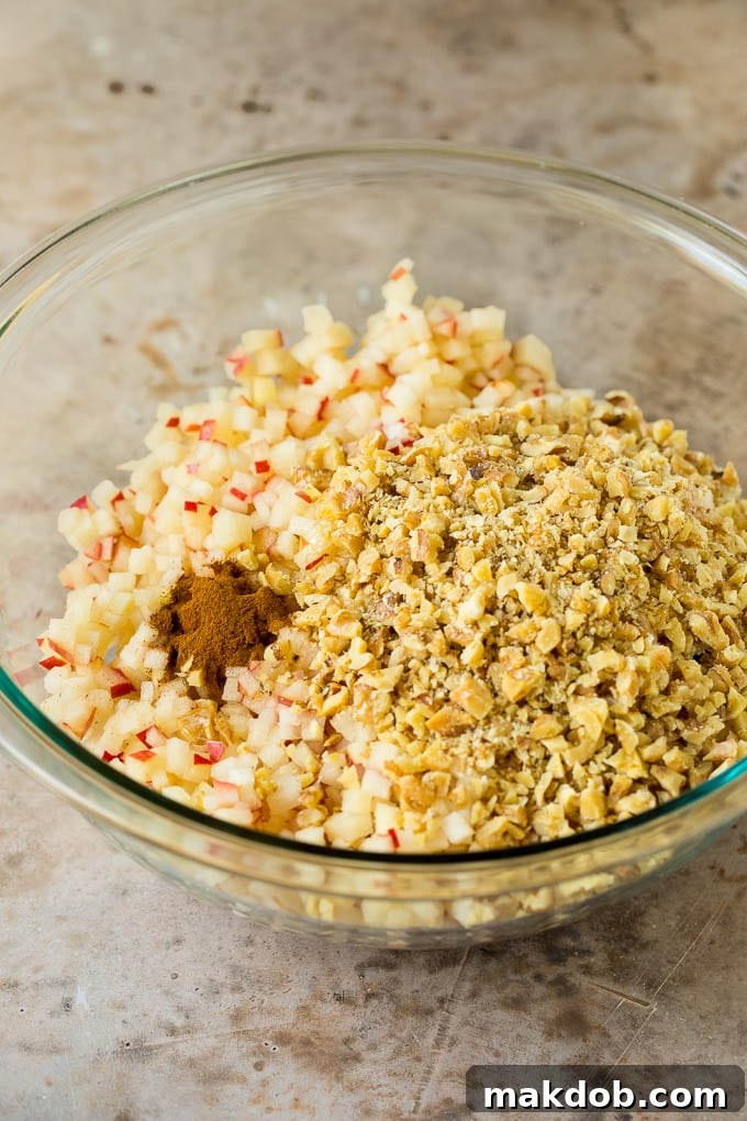 This charoset recipe is a blend of apples, walnuts and honey, all mixed together to make a sweet spread that's an essential part of any Passover meal. All the charoset ingredients—apples, wine, cinnamon, and honey—mixed together in a large bowl, ready to chill.