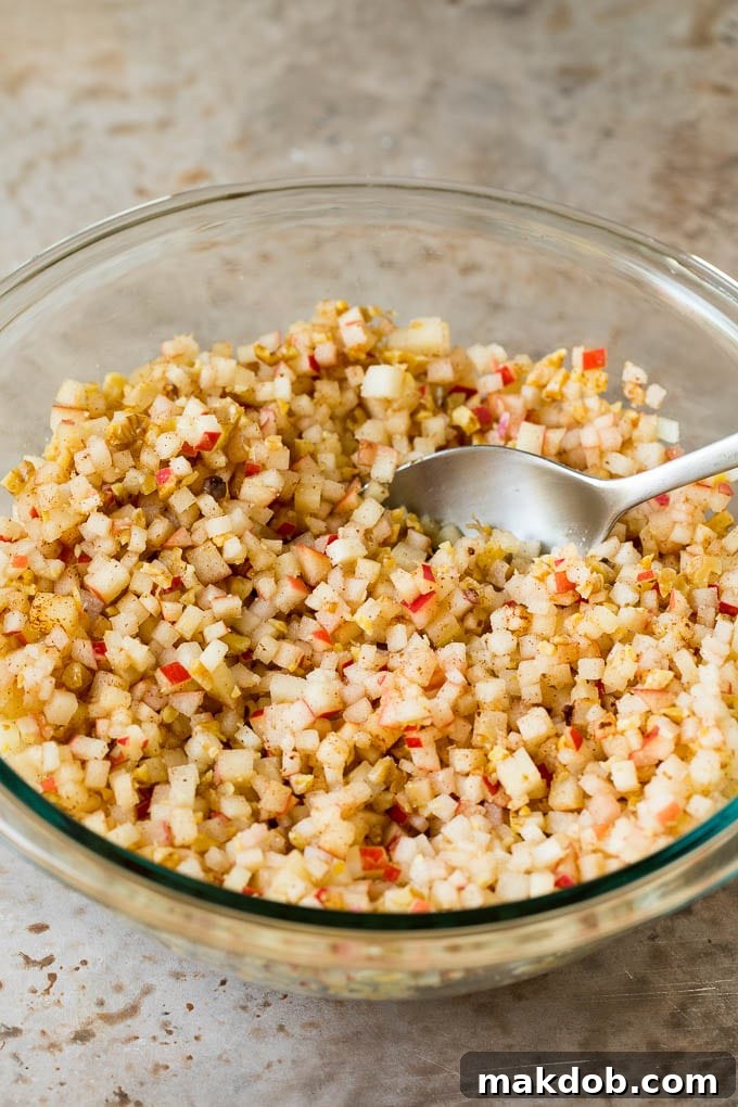 This charoset recipe is a blend of apples, walnuts and honey, all mixed together to make a sweet spread that's an essential part of any Passover meal. A mixing bowl filled with finely diced apples, cinnamon, and honey, before the final mix.