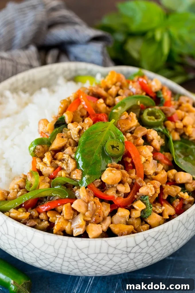 A vibrant bowl of homemade Thai Basil Chicken (Pad Krapow Gai) served over fluffy white rice, garnished with fresh basil leaves.