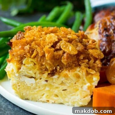 A portion of noodle kugel on a plate served with chicken and vegetables.