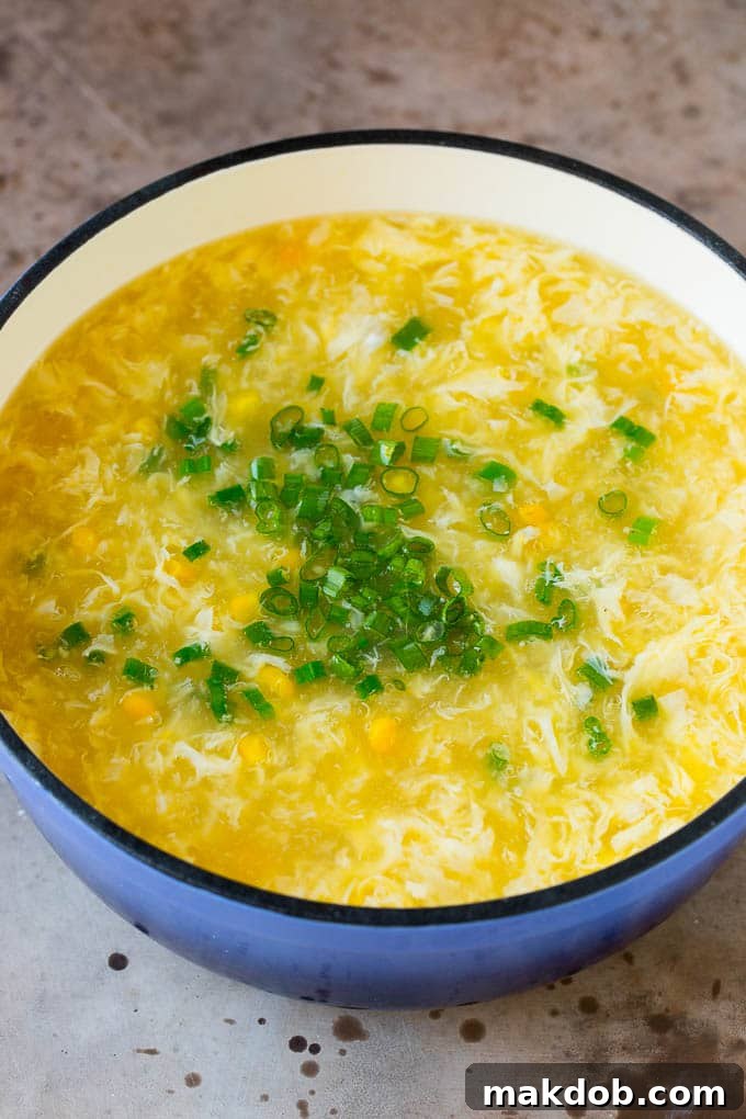 A pot of soup with corn and green onions stirred in.